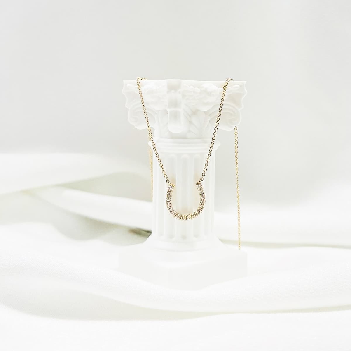 Gold horseshoe pendant necklace with diamond accents for good luck